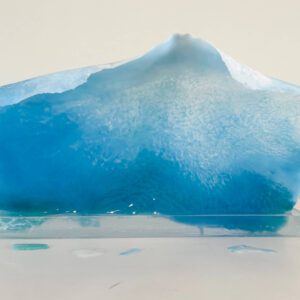 Available, July, 2025. A translucent blue resin sculpture resembling an iceberg, displayed against a white background.